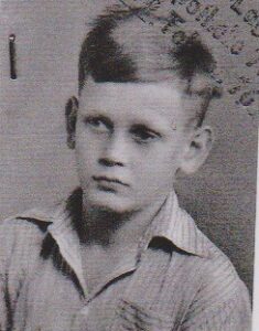 Biało czarna fotografia legitymacyjna przedstawiająca kilkuletniego chłopca ubranego w koszulę.